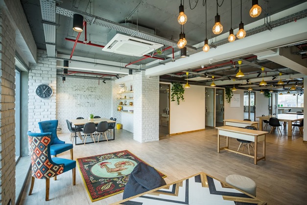 An open plan office decorated with various pendant lights and cosy chairs